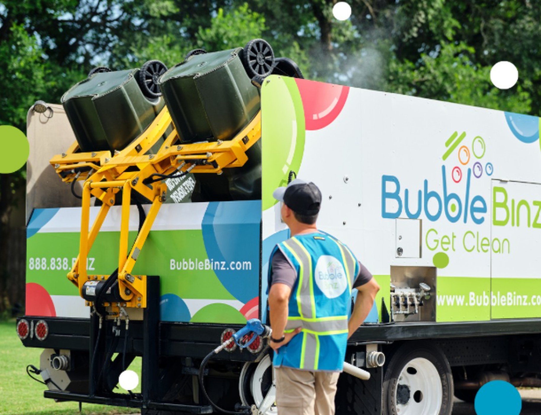 Bubble Binz technician servicing trash bins at the back of a branded truck